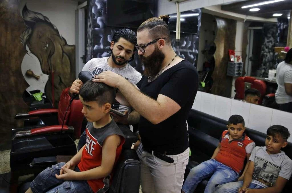 In this Friday, July 14, 2017 photo, Muhannad Khaled Omar, right, prepares to create an image of U.S. President Donald Trump on the back of a customer's head at his barber shop in Burj al-Barajneh, southern Beirut, Lebanon. In a city full of hair stylists, Omar stands out. He is a 26 year-old Palestinian-Syrian hair stylist known for shaving celebrity portraits into clients’ hair. (AP)