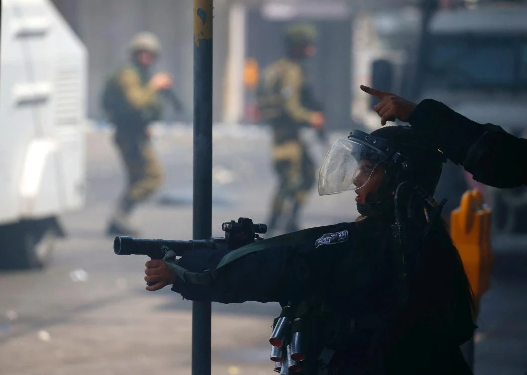Israeli security forces aim their guns towards Palestinian demonstrators in the city of Hebron in the Israeli-occupied West Bank, on July 21, 2017, during a protest by Palestinians in support of the Al-Aqsa mosque compound after Israeli police barred men under 50 from entering the Old City of Jerusalem for Friday Muslim prayers. The ban came after Israeli ministers decided not to order the removal of metal detectors erected at entrances to the Al-Aqsa mosque compound, known to Jews as the Temple Mount, following an attack nearby a week ago that killed two policemen. (AFP)