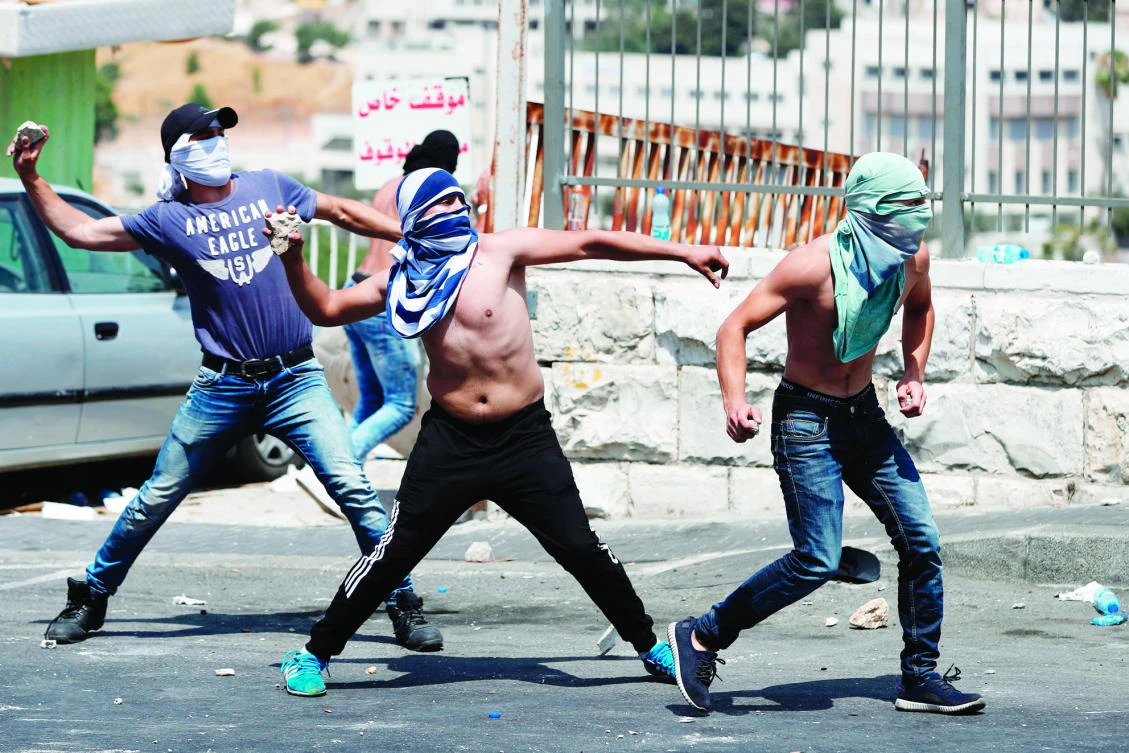 Palestinians hurl stones toward Israeli forces outside Jerusalem’s Old City on Friday. (AFP)
