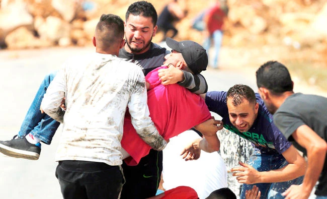 Palestinian youths evacuate a wounded protester during clashes with Israeli border guards in the village of Kubar, west of Ramallah, on Saturday. (AFP)