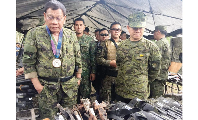 Philippine President Rodrigo Duterte, left, and military chief Eduardo Ano, right, examine Thursday seized weaponry from militants during a visit to a military camp in Marawi on the southern island of Mindanao. (AFP)