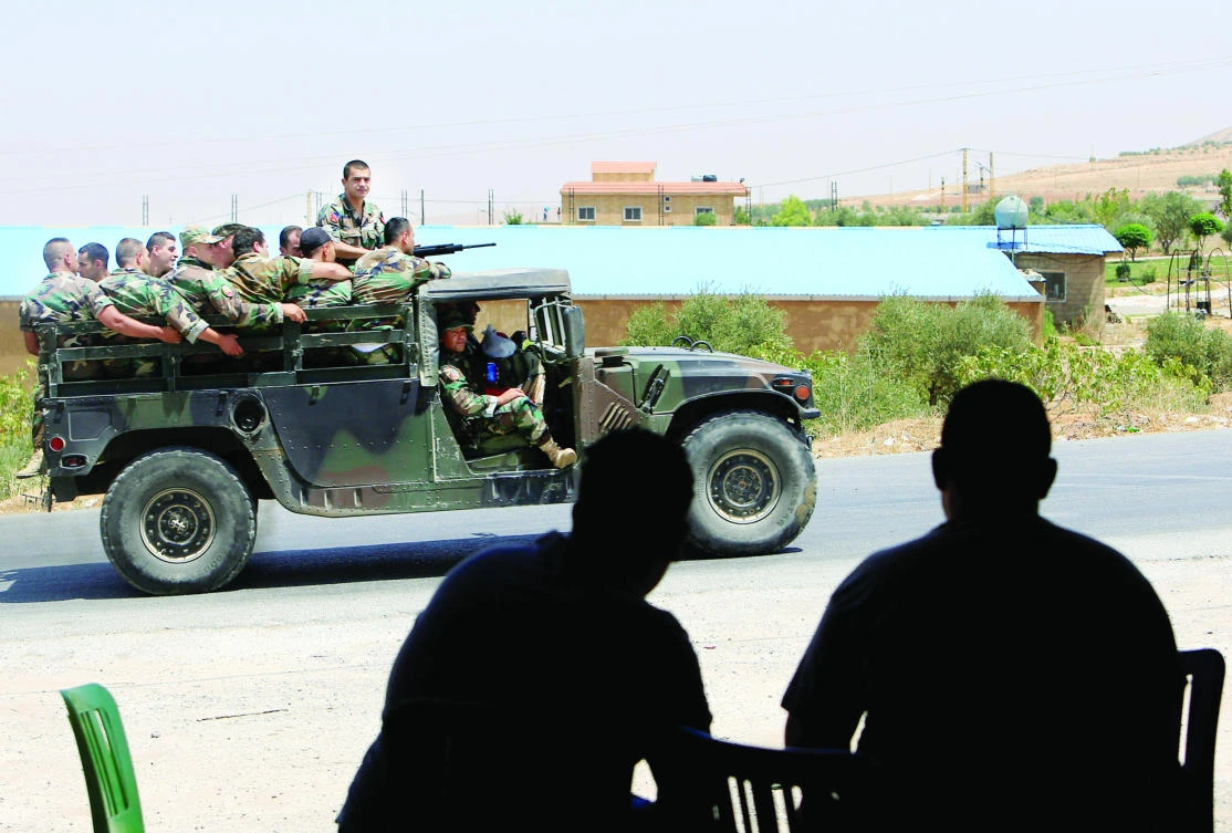 People watch as Lebanese soldiers patrol a street in Labwe at the entrance of the border town of Arsal Sunday. (Reuters)
