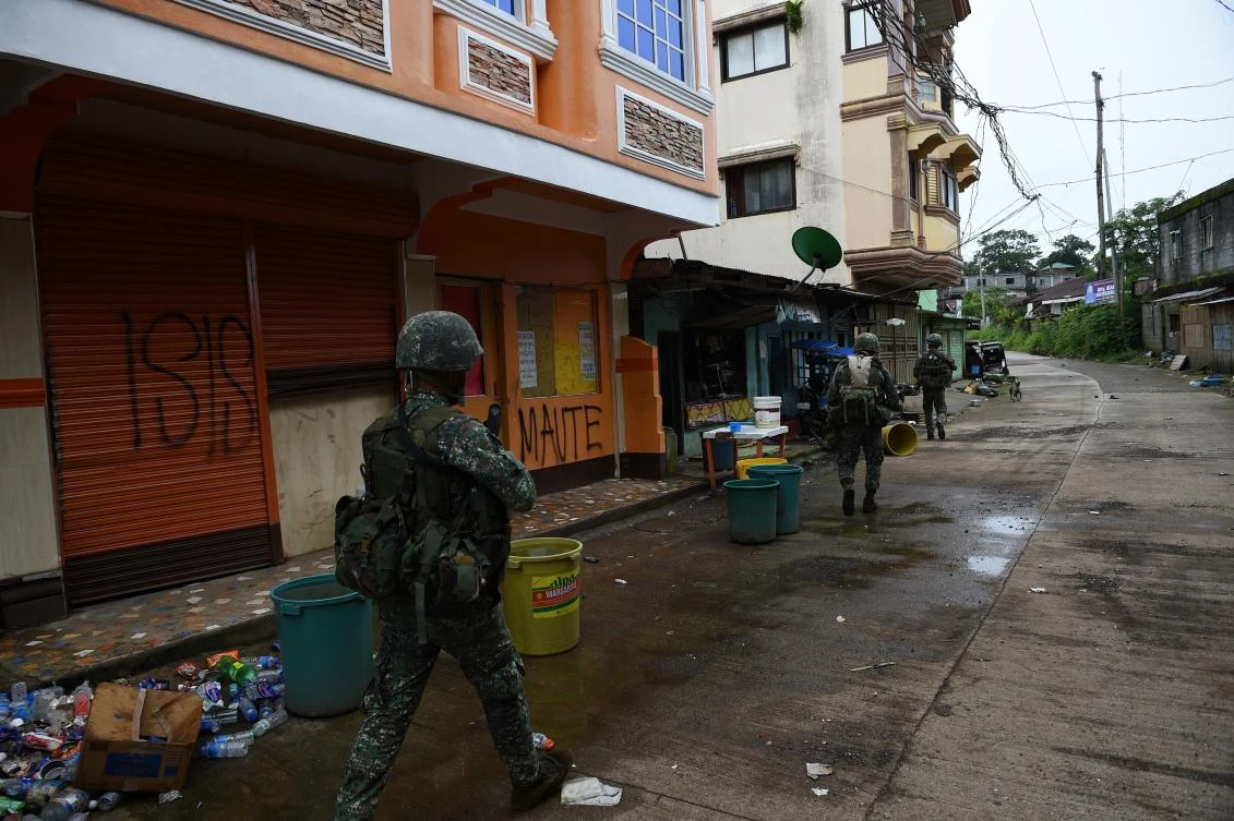Philippine Marines walk past graffiti on shopfronts as they patrol a deserted street at the frontline in Marawi, on the southern island of Mindanao on July 22, 2017. The Philippine Congress on July 22 voted to extend President Rodrigo Duterte's declaration of martial law in the south until the end of the year to defeat Islamist gunmen. (AFP)