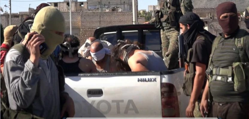 This Sunday, July 9, 2017 photo, released by Ibaa news agency, the communications arm of the al Qaeda-linked Levant Liberation Committee, outlet that is consistent with independent AP reporting, shows al-Qaida-linked fighters after they detained alleged members of the Islamic State group in the northwestern Syrian village of Sarmin in Idlib province. Syrian rebels and opposition activists say an al-Qaida-linked group is on the verge of snuffing out what remains of the 2011 Syrian uprising against President Bashar Assad in northwest Syria. Arabic reads, "Detaining members of the Islamic State group in the city of Sarmin." (AP)