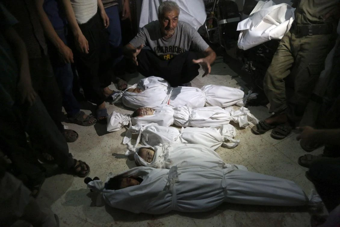 Syrians gather around the bodies of children wrapped in shrouds at a make-shift hospital following shelling on the rebel-held town of Arbin, east of the capital, late on July 24, 2017. Women and children were among the dead in the 11:30 pm (2030 GMT) strike on Arbin in the Eastern Ghouta rebel enclave where the government declared a ceasefire on July 22, the Syrian Observatory for Human Rights said. (AFP)