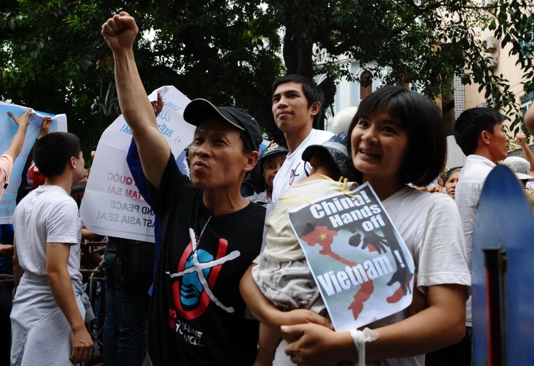 This picture taken on July 8, 2012 shows Tran Thi Nga (R) holding her son and an anti-China poster as she takes part in an anti-China rally in Hanoi. A Vietnamese activist was jailed for nine years on July 25, 2017 for "anti-state activity", her lawyer said, the second such heavy sentence handed down by the authoritarian state in less than a month. (AFP)