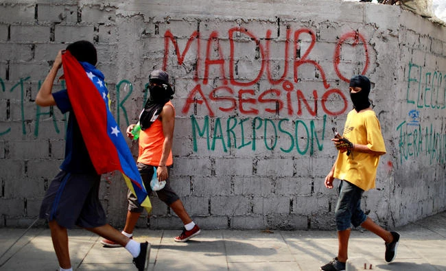 Demonstrators walk past a graffiti that reads "Murderer Maduro" during a strike called to protest against Venezuelan President Nicolas Maduro's government in Caracas, Venezuela on Wednesday. (REUTERS/Marco Bello)
