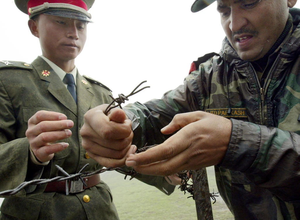 (FILES) This file photo taken on July 5, 2006 shows a Chinese soldier (L) and Indian soldier placing a barbed wire fence following a meeting of military representatives at the Nathu La border crossing between India and China in India's northeastern Sikkim state. A border standoff between Chinese and Indian troops on a remote Himalayan plateau has heightened long-standing tensions while ensnaring a tiny kingdom, Bhutan, between the two nuclear-armed powers. The row has festered for more than a month by the end of July 2017 as India and China refuse to back down in the distant but strategically key territory, reflecting the historic mistrust between the Asian giants. (AFP)