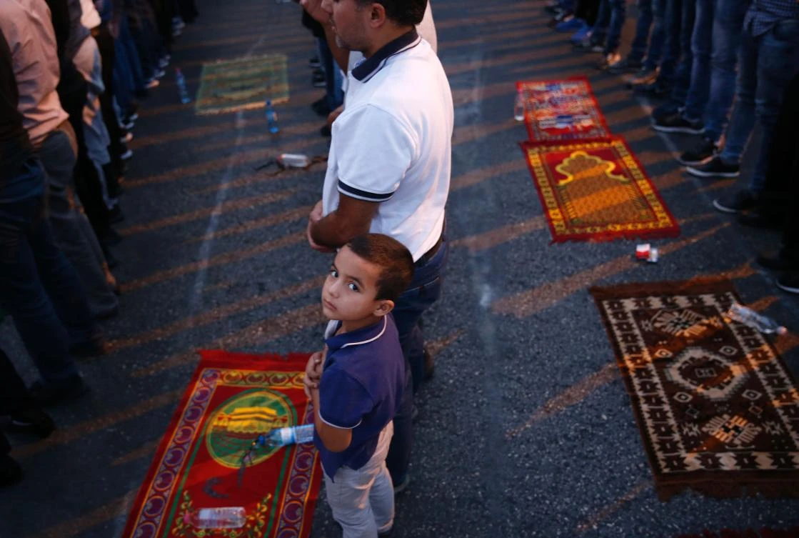 A young boy looks on as Palestinian Muslim worshippers pray outside Lion's Gate which leads to the Al-Aqsa compound in Jerusalem's Old City on July 26, 2017, during an ongoing standoff between Israel and Muslim worshippers at the holy site. Muslims have refused to enter the site and have prayed in the streets outside for more than a week after Israel installed new security measures at the Haram al-Sharif compound, known to Jews as the Temple Mount. (AFP)