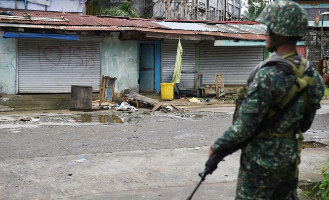 A Philippine soldier standing in front of a graffiti in a deserted neighbourhood in Marawi on July 22, 2017. Western governments are warning their citizens against travelling to nearly all of the southern third of the Philippines, citing the rising threats of terror attacks and kidnappings by Islamist militants. (AFP)