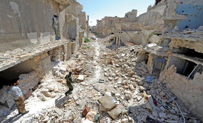 Members of the Asayish security force walk on debris of damaged buildings in Aleppo's Sheikh Maqsoud neighborhood, Syria in this July 15 photo. (Reuters)