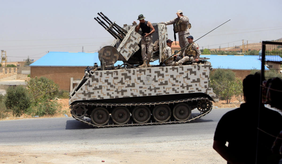 A man watches Lebanese army soldiers ride on a military tank in Labwe, at the entrance of the border town of Arsal, in Bekaa Valley, Lebanon, on July 27, 2017. (REUTERS/Ali Hashisho)