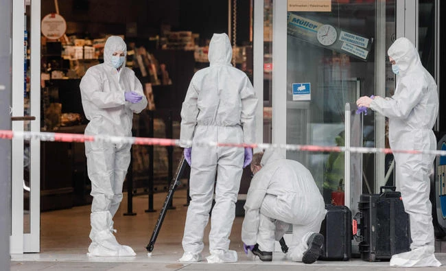 Police investigators work at the area around a supermarket in the northern German city of Hamburg, where a man killed one person and wounded several others in a knife attack, on Friday. (AFP / dpa / Markus Scholz)