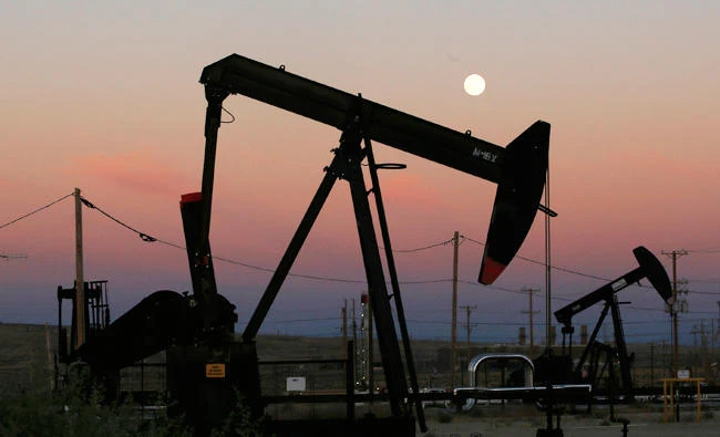 In this June 8, 2017 photo, oil derricks are busy pumping as the moon rises near the La Paloma Generating Station in McKittrick, Calif. (AP)