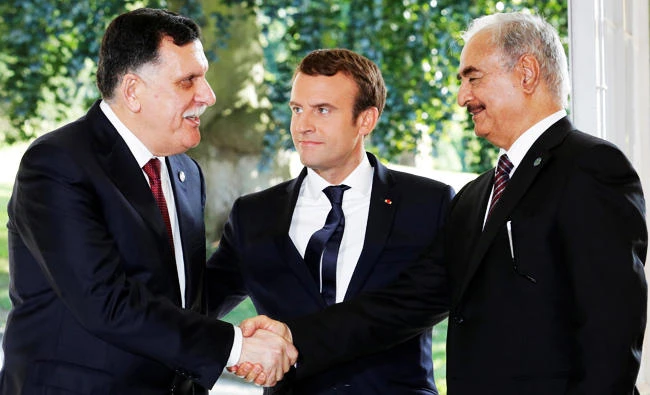 French President Emmanuel Macron stands between Libyan Prime Minister Fayez al-Sarraj (L), and General Khalifa Haftar (R), commander in the Libyan National Army (LNA), who shake hands after talks over a political deal to help end Libya's crisis in La Celle-Saint-Cloud near Paris, France, in this July 25, 2017 photo. (REUTERS)