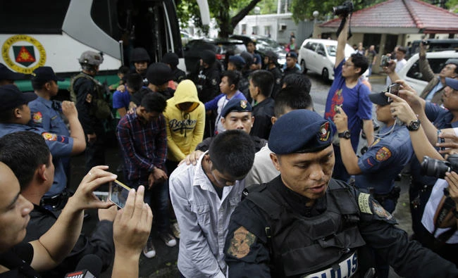 Police escort men suspected to be enroute to reinforce the Marawi militants as they arrive at the Department of Justice in Manila, Philippines on Friday. The group were arrested in southern Ipil town and Zamboanga city and were flown under heavy guard Friday to Manila, where they denied before prosecutors that they were aiming to back up the extremists. (AP Photo/Aaron Favila)