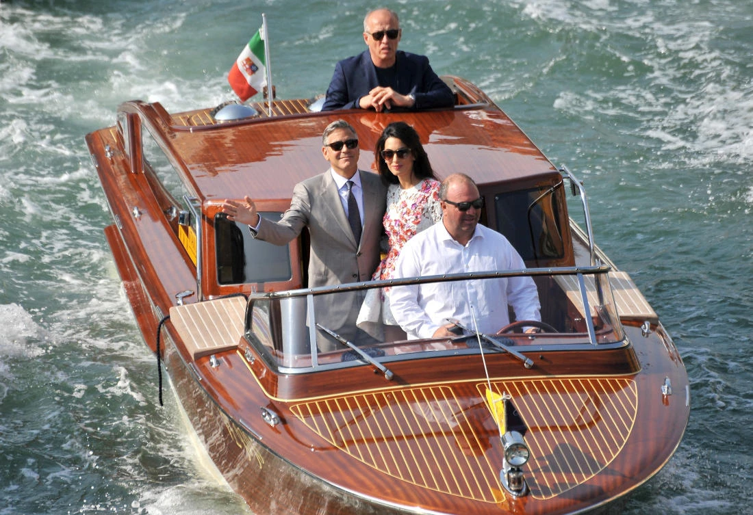 FILE - In this Sept. 28 2014 file photo, George Clooney and his wife Amal Alamuddin, cruise the Grand Canal after leaving the Aman luxury Hotel in Venice, Italy, Sunday, Sept. 28, 2014. This year's Venice Film Festival will include a crime comedy by George Clooney, a Guillermo del Toro fantasy and a Darren Aronofsky thriller. Organizers announced a 21-film competition lineup Thursday that includes the Clooney-directed "Suburbicon," the story of a home invasion gone wrong starring Matt Damon and Julianne Moore. (AP)