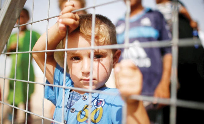 A displaced Iraqi boy waits with his family on Saturday for supplies at Hammam Al-Alil camp, south of Mosul. (Reuters)