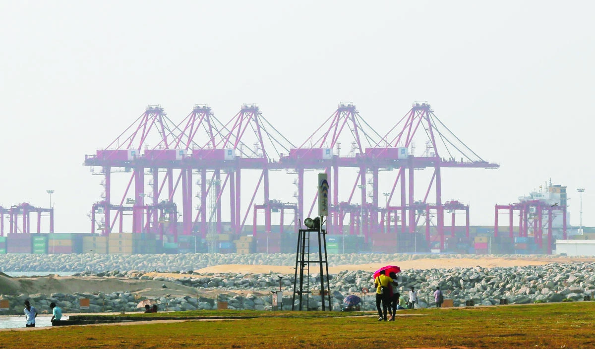 A couple walk on the Galle Face green as the China Port City project is seen behind in Colombo, Sri Lanka. (AP)