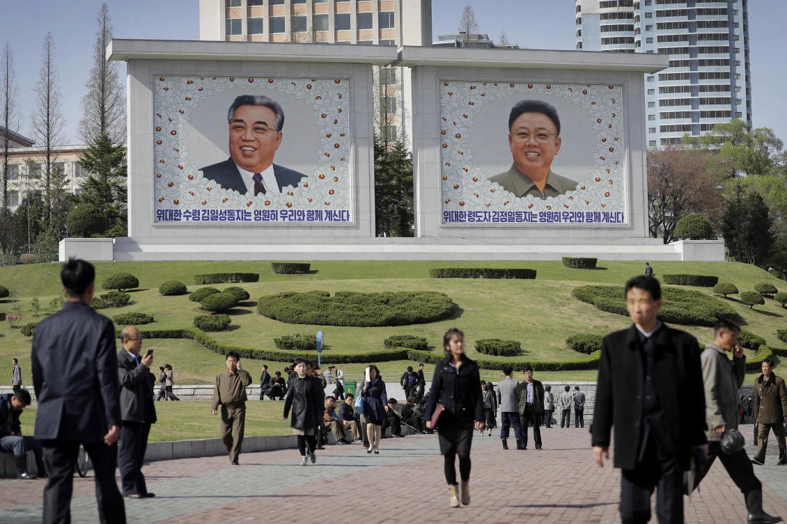 FILE - In this April 18, 2017, file photo, people walk beneath portraits of late leaders, Kim Il Sung, left, and Kim Jong Il, in Pyongyang, North Korea. For generations, propaganda about the Kim family was all that most North Koreans knew, a mythology of powerful but tender-hearted rulers who protect their people against a hostile world. (AP)