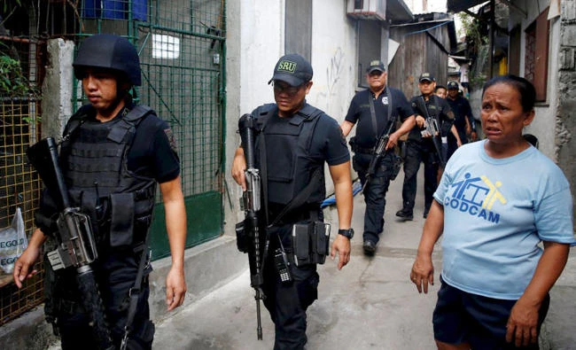 Police from the SWAT team walk past a resident during an anti-drugs operation in Mandaluyong, metro Manila in the Philippines in this file photo. (Reuters)