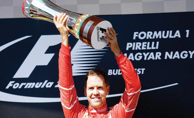 Ferrari’s German driver Sebastian Vettel celebrates on the podium with his trophy after winning the Formula One Hungarian Grand Prix at the Hungaroring racing circuit in Budapest on Sunday. (AFP)