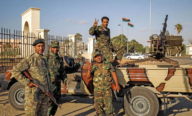 Members of the self-styled Libyan National Army, loyal to the country's east strongman Khalifa Haftar, flash the victory gesture next to a vehicle-mounted heavy gun in the eastern city of Benghazi on July 27, 2017. Libya’s internationally recognized parliament is based in Benghazi and allied with Haftar's forces. (AFP / Abdullah Doma)