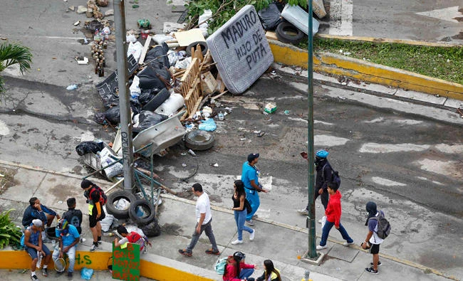 People walk past a street barricade that includes a mattress with the words "Maduro son of a bitch" after clashes broke out while the Constituent Assembly election was being carried out in Caracas, Venezuela, on Sunday. (REUTERS)
