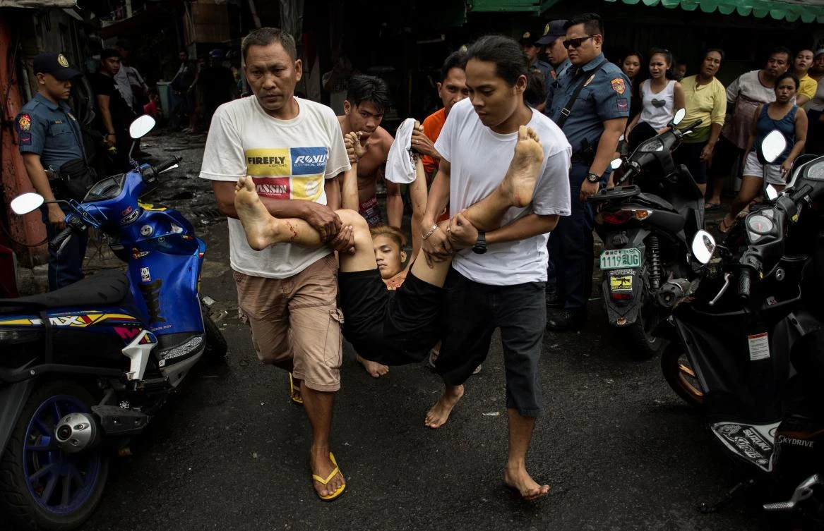 EDITORS NOTE: Graphic content / Residents carry a body of an alleged drug dealer killed during a large scale anti-drug raid by the police at a slum community in Manila on July 20, 2017. One resident was killed in the raid according to police. President Rodrigo Duterte swept to an election victory last year largely on a pledge to wipe out his nation's illegal drugs trade within three to six months, saying he would do so by killing thousands of people. Duterte fulfilled his vow on the death toll, drawing condemnation from rights groups who warned he may be orchestrating a crime against humanity as police and unknown assassins filled slums with bullet-ridden corpses. (AFP)