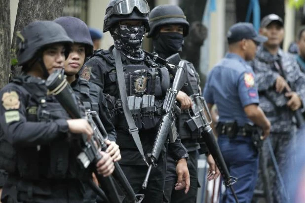 Armed police keep watch as men suspected of being en route to reinforce Marawi militants arrive at the Department of Justice in Manila, Philippines on Friday. (AP)