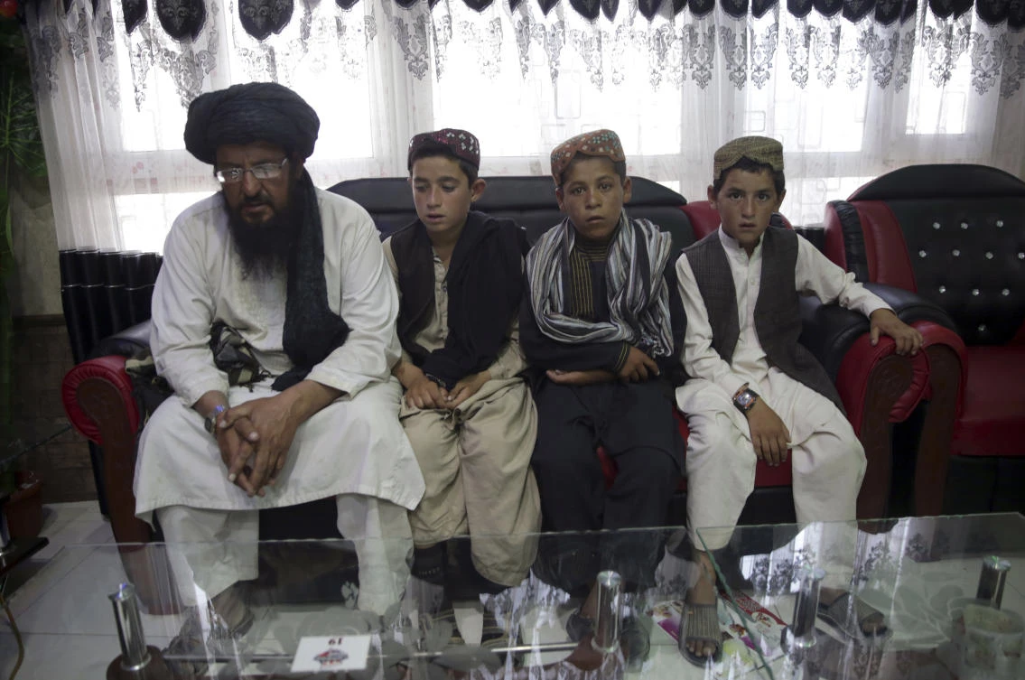 In this photo taken on Tuesday, July 25, 2017, Mohammed Naseer, with black turban, and three children wait for their food iN a Pizza Restaurant in Kabul, Afghanistan. Mohammed Naseer spent several weeks arranging for his son, a nephew and several other children from his district of Ander in Ghazni province to go to Quetta to study the Quran. (AP)