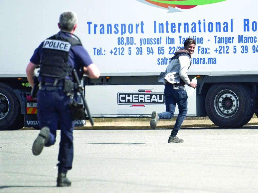 A policemen chases a refugee at a lorry park in Calais, France, in this file photo. (AFP)