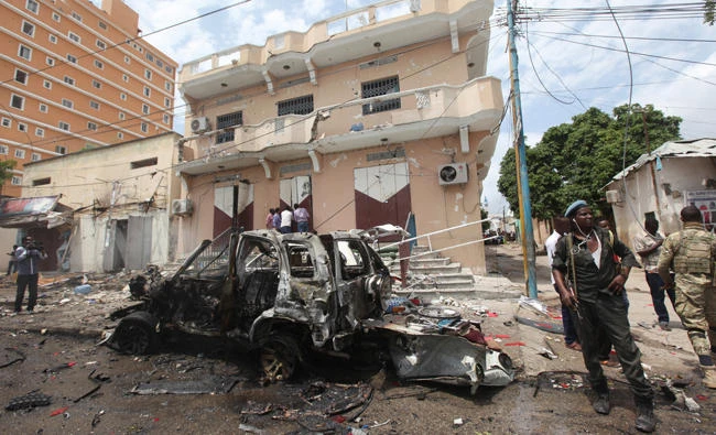 A Somali soldier stands on guard next to a destroyed car near a popular mall after a car bomb attack in Mogadishu, Somalia, on July 30, 2017. Somalia's government on Monday said it believes the strike killed a high-level al-Shabab commander responsible for several deadly bombings in the capital. (AP Photo/Farah Abdi Warsameh)