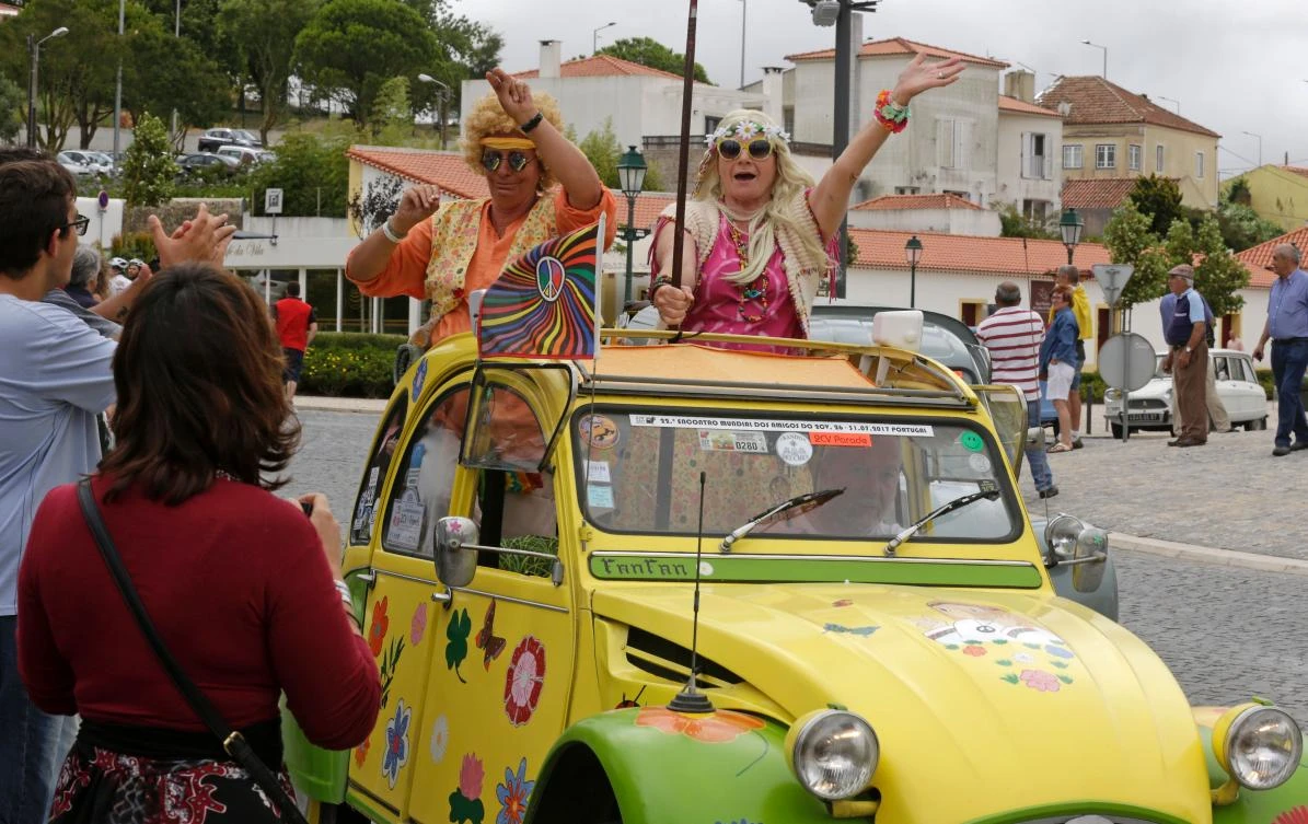 Participants and locals celebrate in Mafra the arrival of the the parade of Citroen classic cars 2CV during the World 2017 2CV Meeting July 30, 2017. The event is held between the 26th and the 31st of July 2017, 30 years after Portugal hosted the seventh 2CV World Meeting in 1987, and will include activities ranging from an open air fair, a competition to disassemble and reassemble, an "elegance" contest for original and modofied 2CV's, a chimes concert, to a short term 2CV museum hosted by the Marfa national palace featuring vehicles from the Citroen Heritage collection purposely brought from Paris. / AFP / JOSE MANUEL RIBEIRO