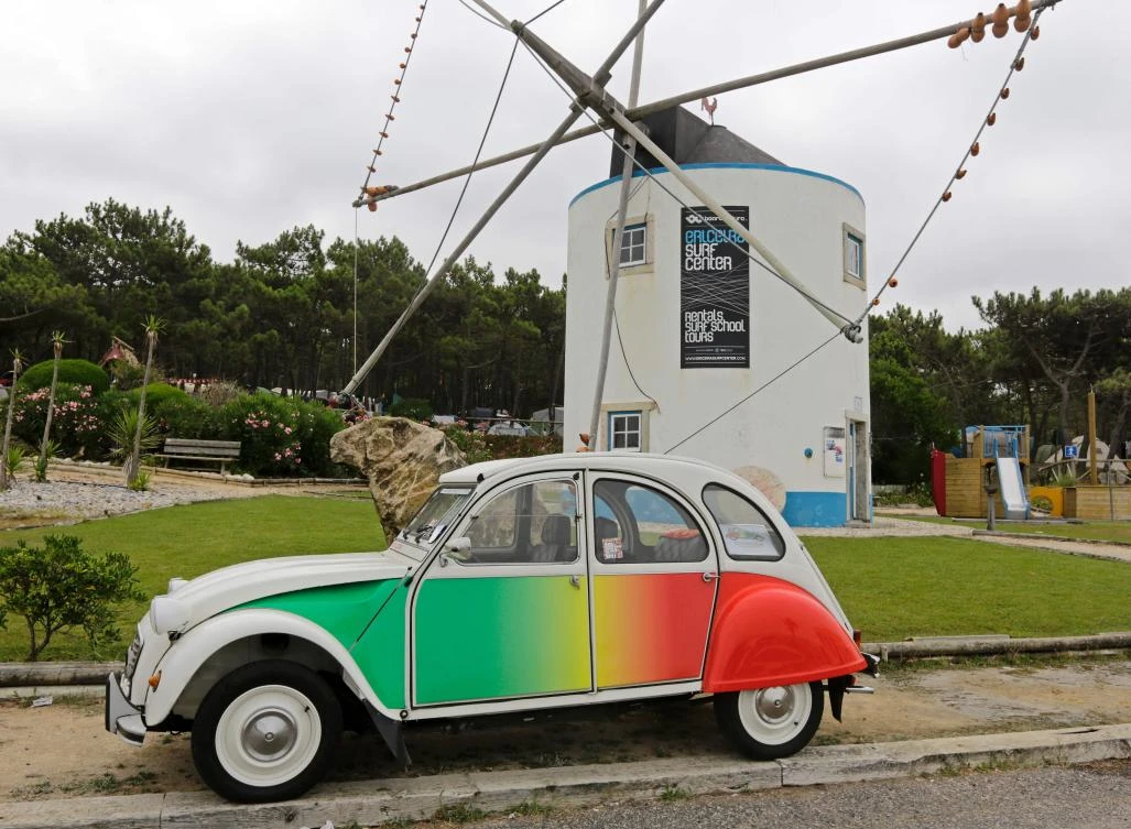 A Citroen classic 2CV painted with Portuguese flag colours is parked near a traditional wind mill at Ericeira village during the World 2017 2CV Meeting July 30, 2017. The event is held between the 26th and the 31st of July 2017, 30 years after Portugal hosted the seventh 2CV World Meeting in 1987, and will include activities ranging from an open air fair, a competition to disassemble and reassemble, an "elegance" contest for original and modofied 2CV's, a chimes concert, to a short term 2CV museum hosted by the Marfa national palace featuring vehicles from the Citroen Heritage collection purposely brought from Paris. / AFP / JOSE MANUEL RIBEIRO