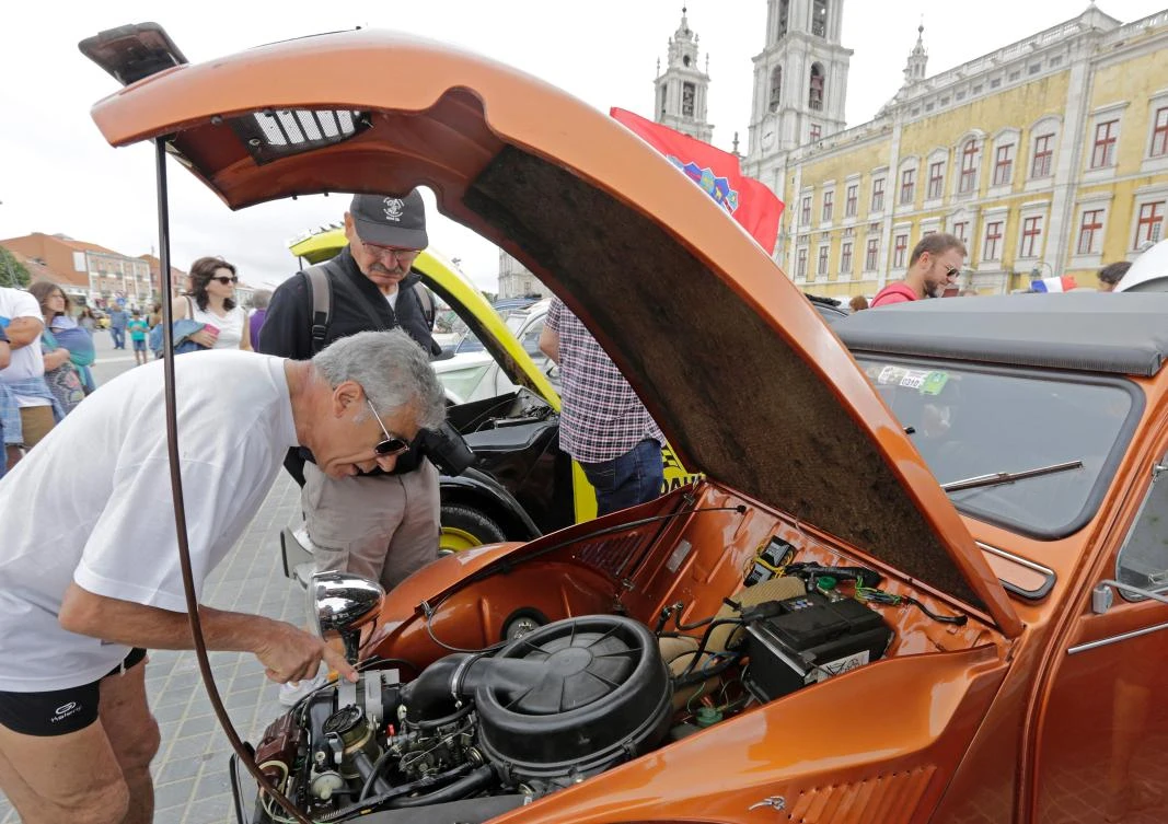 A visitor inspects the engine of a car parked in Mafra after the arrival of the parade of Citroen classic cars 2CV during the World 2017 2CV Meeting July 30, 2017. The event is held between the 26th and the 31st of July 2017, 30 years after Portugal hosted the seventh 2CV World Meeting in 1987, and will include activities ranging from an open air fair, a competition to disassemble and reassemble, an "elegance" contest for original and modofied 2CV's, a chimes concert, to a short term 2CV museum hosted by the Marfa national palace featuring vehicles from the Citroen Heritage collection purposely brought from Paris. / AFP / JOSE MANUEL RIBEIRO