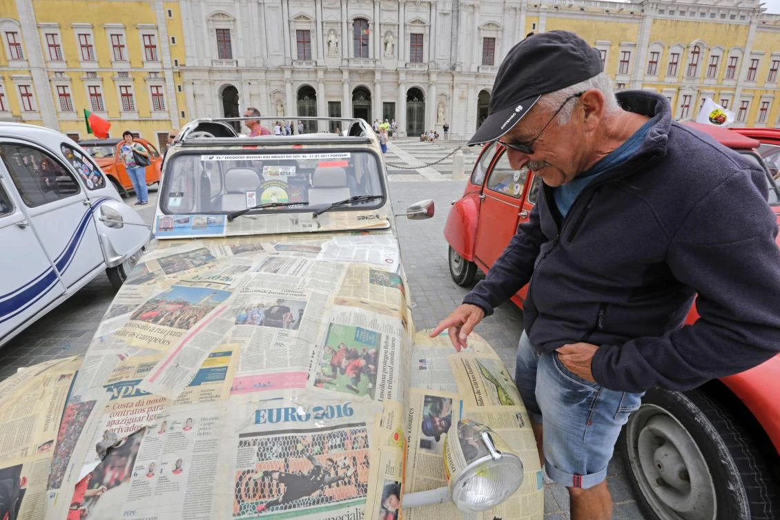 Visitor reads the papers painted on a car parked in Mafra after the arrival of the parade of Citroen classic cars 2CV during the World 2017 2CV Meeting July 30, 2017. The event is held between the 26th and the 31st of July 2017, 30 years after Portugal hosted the seventh 2CV World Meeting in 1987, and will include activities ranging from an open air fair, a competition to disassemble and reassemble, an "elegance" contest for original and modofied 2CV's, a chimes concert, to a short term 2CV museum hosted by the Marfa national palace featuring vehicles from the Citroen Heritage collection purposely brought from Paris. / AFP / JOSE MANUEL RIBEIRO