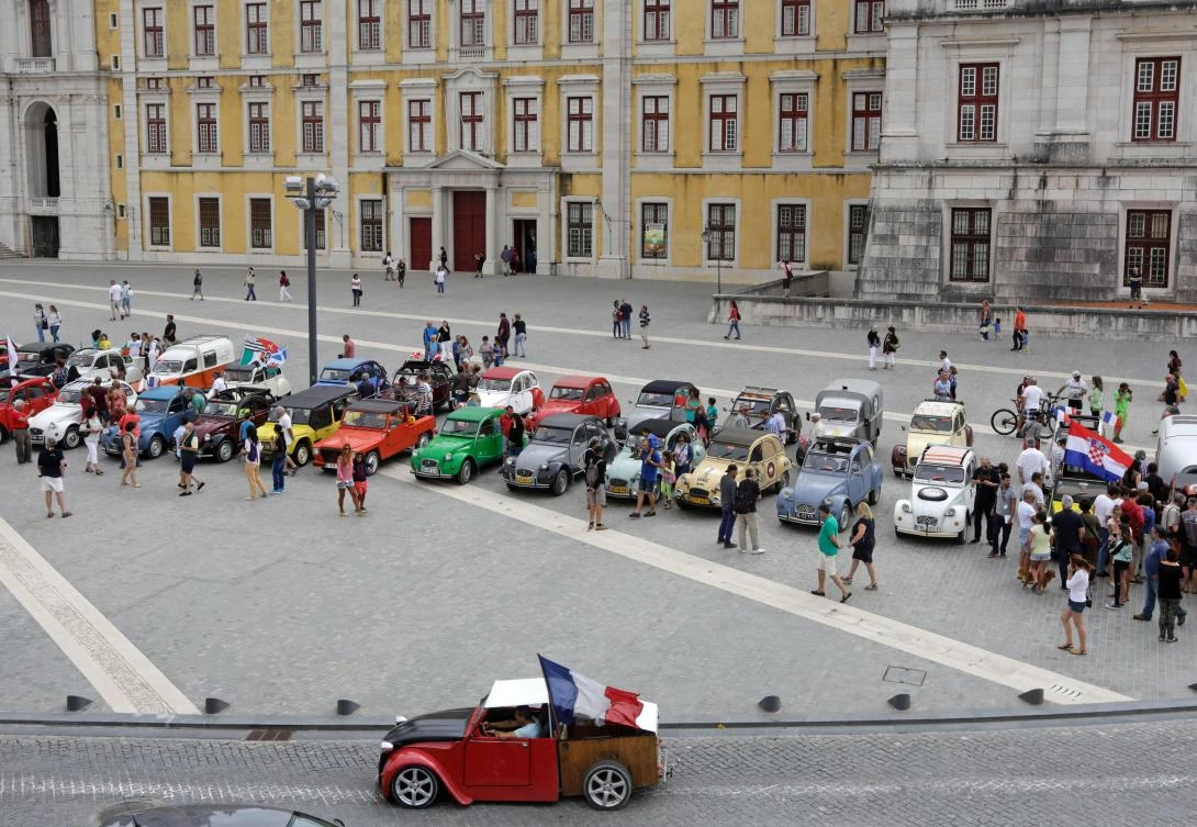 A car with a French flag passes in front the parked cars in Mafra after the parade of Citroen classic cars 2CV during the World 2017 2CV Meeting July 30, 2017. The event is held between the 26th and the 31st of July 2017, 30 years after Portugal hosted the seventh 2CV World Meeting in 1987, and will include activities ranging from an open air fair, a competition to disassemble and reassemble, an "elegance" contest for original and modofied 2CV's, a chimes concert, to a short term 2CV museum hosted by the Marfa national palace featuring vehicles from the Citroen Heritage collection purposely brought from Paris. / AFP / JOSE MANUEL RIBEIRO
