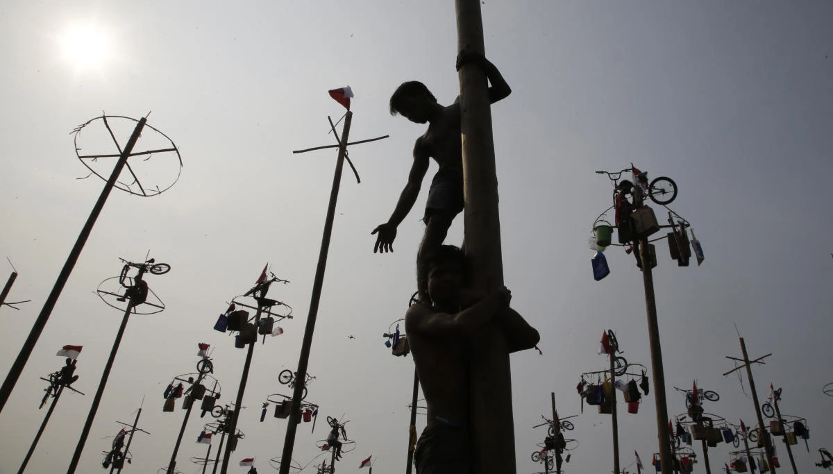 Participants assist each other in greased-pole climbing competition held as a part of independence day celebration at Ancol Beach in Jakarta, Indonesia, Thursday, Aug 17, 2017. Contestants race up to grab items ranging from buckets to bicycles hanging from the top of the poles as prize. Indonesia is celebrating its 72th anniversary of independence from the Netherlands. (AP Photo/Achmad Ibrahim)