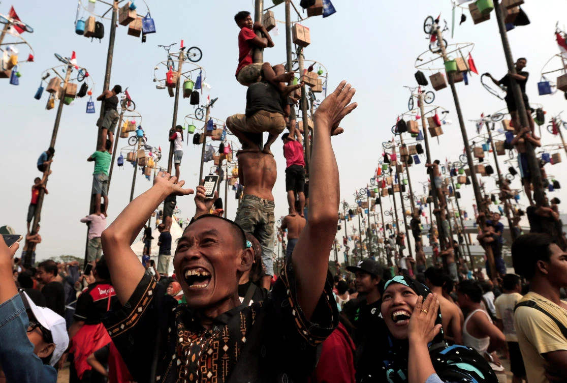 A couple reacts as their colleague wins a bicycle during greased pole competition during the celebration of Independence Day at Ancol Dreamland Park in Jakarta, Indonesia August 17, 2017. REUTERS/Beawiharta