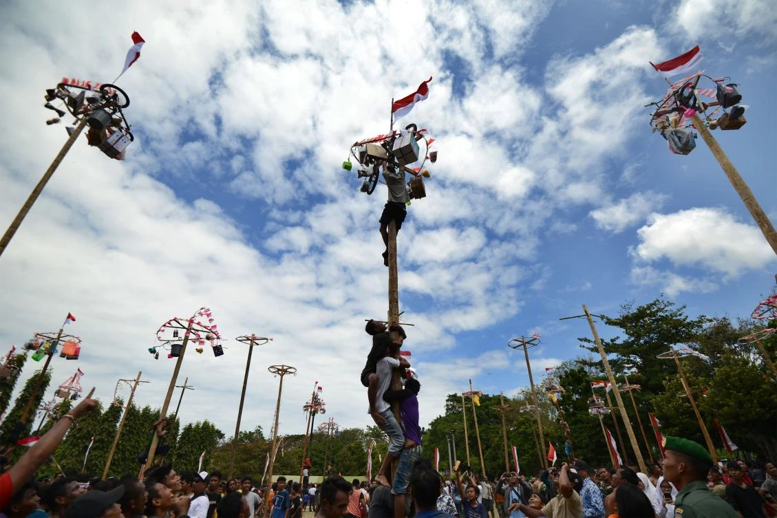 People climb greased poles, on which prizes and flags are attached, to celebrate Indonesia's Independence Day in Denpasar on the Indonesian resort island of Bali on August 17, 2017. Indonesia marked the 72nd anniversary of its independence from Dutch rule on August 17. / AFP / Sonny TUMBELAKA