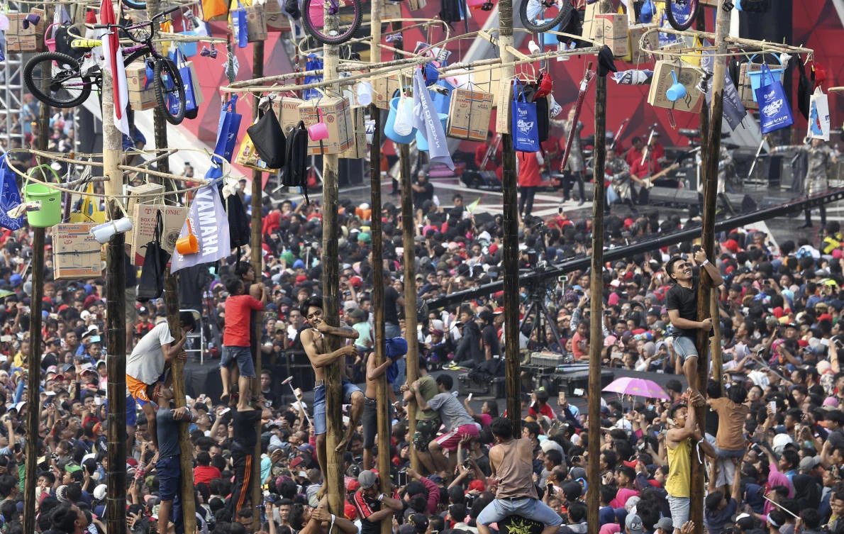 Participants struggle during a greased-pole climbing competition held as a part of independence day celebration at Ancol Beach in Jakarta, Indonesia, Thursday, Aug 17, 2017. Contestants race up to grab items ranging from buckets to bicycles hanging from the top of the poles as prize. Indonesia is celebrating its 72th anniversary of independence from the Netherlands. (AP Photo/Achmad Ibrahim)
