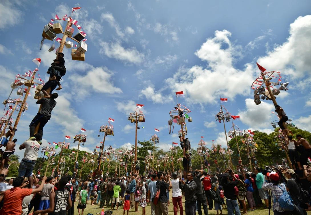 People climb greased poles, on which prizes and flags are attached, to celebrate Indonesia's Independence Day in Denpasar on the Indonesian resort island of Bali on August 17, 2017. Indonesia marked the 72nd anniversary of its independence from Dutch rule on August 17. / AFP / Sonny TUMBELAKA