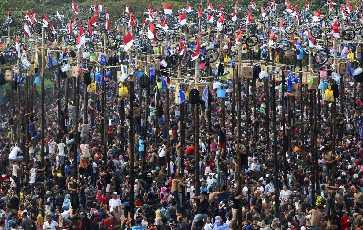 Participants struggle during a greased-pole climbing competition held as a part of independence day celebration at Ancol Beach in Jakarta, Indonesia, Thursday, Aug 17, 2017. Contestants race up to grab items ranging from buckets to bicycles hanging from the top of the poles as prize. Indonesia is celebrating its 72th anniversary of independence from the Netherlands. (AP Photo/Achmad Ibrahim)