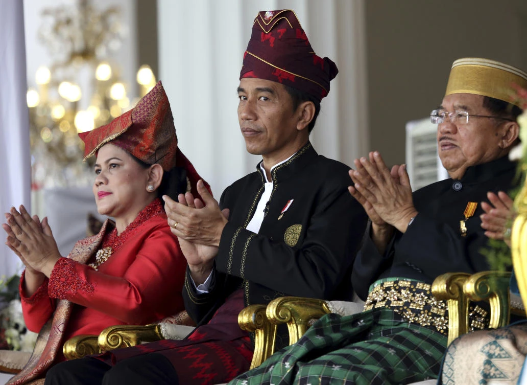 Indonesia's President Joko Widodo, center, his wife Iriana, left, and deputy Jusuf Kalla applaud during a flag hoisting ceremony marking the 72nd anniversary of the country's Independence on Thursday, Aug. 17, 2017, at Merdeka Palace in Jakarta, Indonesia. Indonesia declared its independence from Dutch colonial rule in 1945. (AP Photo/Dita Alangkara)