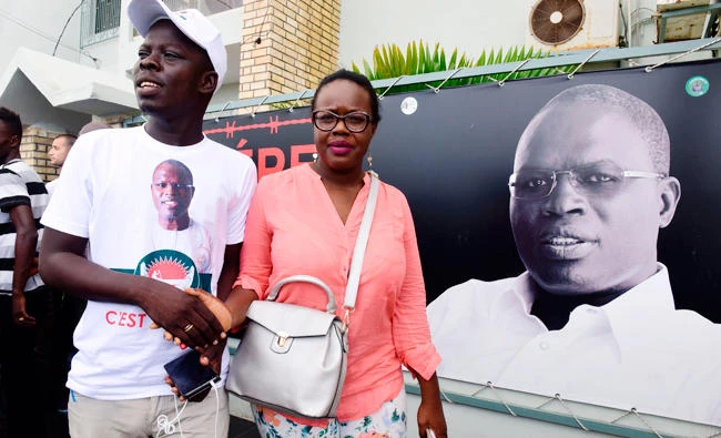 Supporters walk in front of a banner with a picture of Dakar's mayor Khalifa Sall, in jail awaiting trial for what supporters say are politically motivated embezzlement charges, on display in front of his offices in Dakar on Monday, a day after legislative elections. (AFP / SEYLLOU)