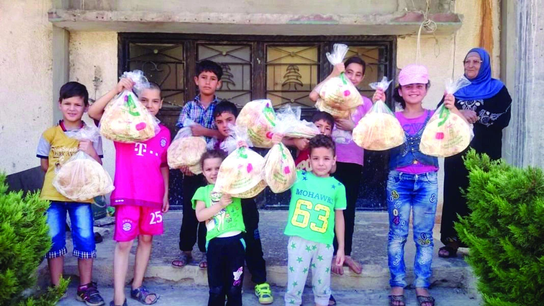 Displaced Syrian children happily carrying bags of bread distributed by the Saudi National Campaign in Lebanon and Syria. (SPA)