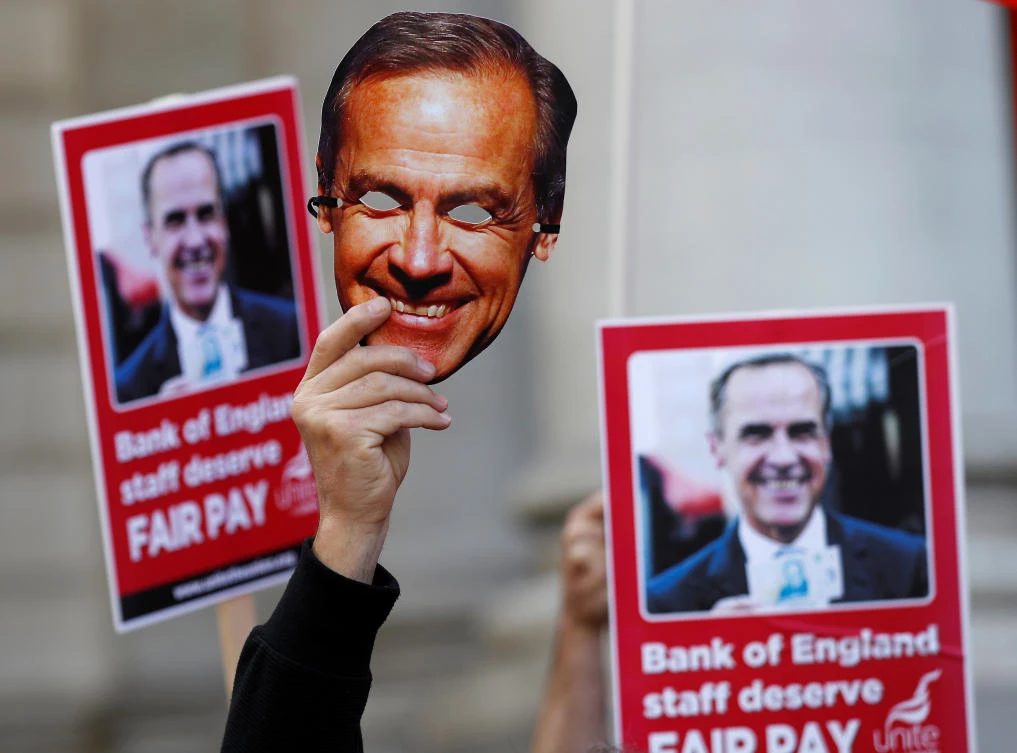 A protester holds up Bank of England Governor Mark Carney mask outside the bank as it staff begins a three day strike over pay, in the City of London, Britain, August 1, 2017. (REUTERS)