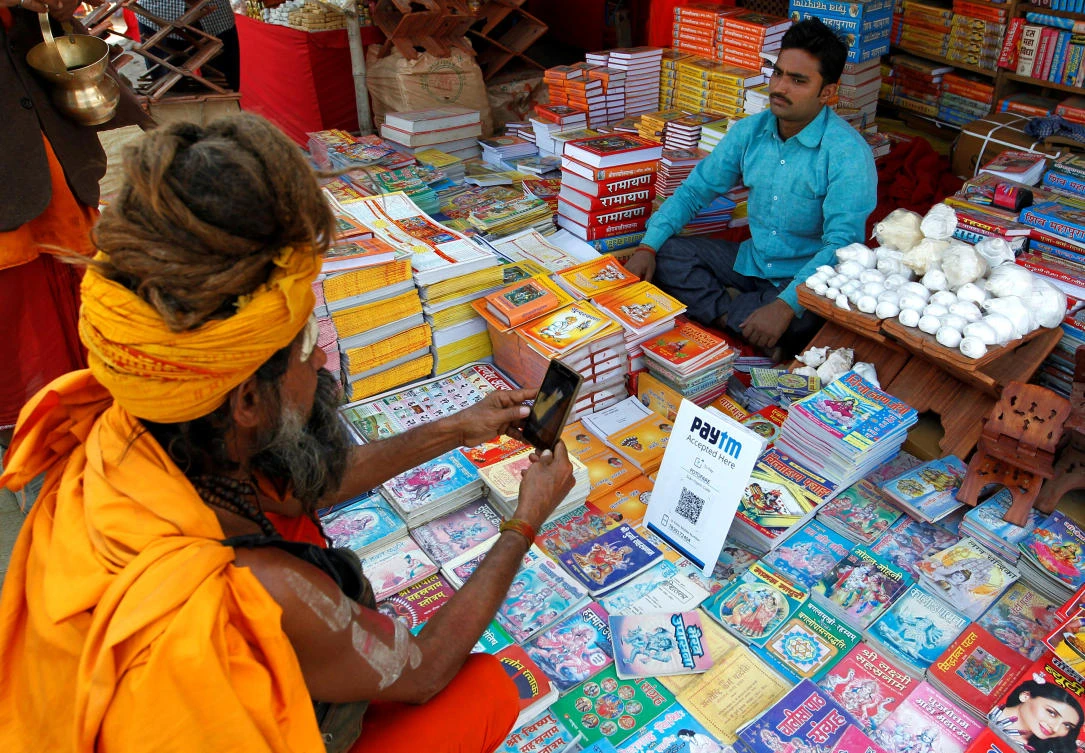 A Sadhu or a Hindu holy man pays the vendor through Paytm, a digital wallet company, after buying a book during the annual religious festival of Magh Mela in Allahabad, India, January 26, 2017. (REUTERS)