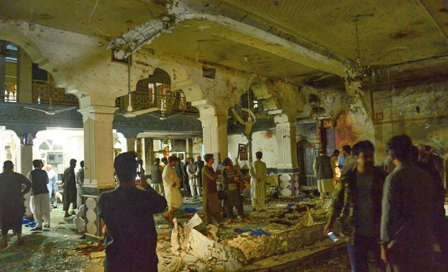 Afghan police officers inspect the site of a suicide bomb attack at a Shiite mosque in Herat on Tuesday. (AFP / Hoshang Hashimi)
